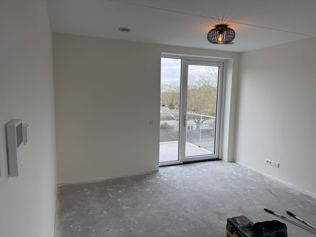 Lege slaapkamer in een nieuw appartement met witte wanden en een deur naar het balkon